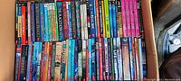 Photo showing rows of paperback books tightly packed in a box, titles visible on spines including 'Game Changers', 'The Real Boy', 'False Prince', and others