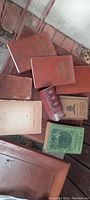 Photo showing a pile of old books with mostly brown covers and some green, titles visible including 'History of Medicine in Maryland' and others.