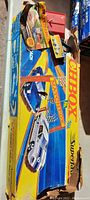 Top view of the brittle and torn original box with colorful graphics showing the blue and yellow double race track setup and included cars images, with visible package wear and cardboard damage.