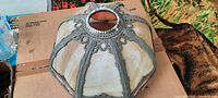 Top view of stained-glass lampshade showing aged and stained opaque glass panels and metal ribbing frame with decorative detailing