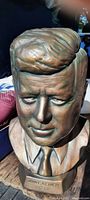 Front view of a vintage kiln fired bust of John F. Kennedy showing detailed facial features and distinctive hairstyle in a bronze-like finish.