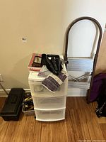 Step stool, toolbox, plastic storage bin with gloves and shovel on top, arranged against wall