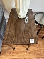 Top view of one wooden end table showing wood grain laminate surface and a white lamp placed on it, with measurement label showing 17x29x22.