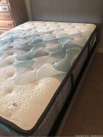 Angled view of mattress top surface on upholstered frame showing quilted pattern