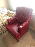 Angled front-right view of red bonded leather armchair showing overall shape and tapered legs