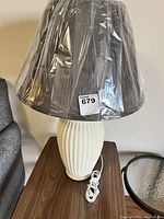 Full view of the white textured ceramic lamp base with the dark pleated lampshade still wrapped in plastic
