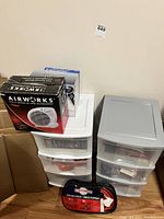 Photo showing plastic storage bins white and gray, Flash Night Airworks fan box, and jumper cables bag