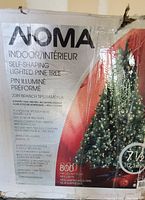 Photo of the original box of the NOMA indoor self-shaping lighted pine tree showing key details such as 7.5 feet height, 2,089 branch tips, 800 clear mini lights, and other specifications.