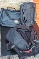 Three black bags including one duffle bag and two laptop bags arranged together.