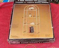 Boxed four tier arched top etagere made of gold metal.