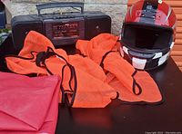 Image displaying the orange safety vest, red plastic table cloth, black Sony CD player, and a red, white, and black full-face motorcycle helmet.