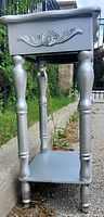 Silver night stand front angle showcasing drawer with decorative carved front and turned legs.