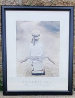 Photo of the framed 'Success is...' picture showing a child sitting outdoors with text below the image.