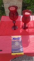 Two red glass candleholders on a red cloth with a Rotary Club Scarborough Ontario banner in front.