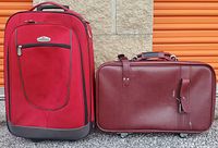 Image showing two red suitcases side by side: a soft fabric upright suitcase and a smaller hard-sided rectangular suitcase.