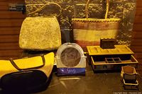 Photo of four women's bags, a silver tray, a wooden jewelry box with multiple compartments, and an oval metal-framed mirror in packaging on a wooden surface.