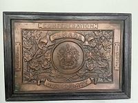 Front view of framed copper plaque with Canadian coat of arms and maple leaf design