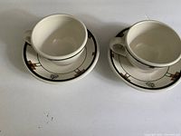 Two Roycroft Inn teacups on matching saucers, showing the full pattern and design.