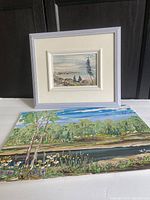 Two acrylic landscape paintings by Wladimir Smirnoff, one smaller framed and one larger unframed, positioned upright against a dark background.