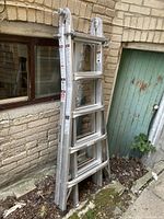 Full view of ladder leaning against brick wall