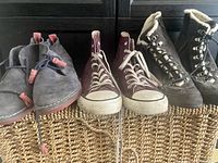 Three pairs of ankle boots shown side by side: grey work boots, purple runners with toggle laces, and blue Hush Puppies lace-up boots.