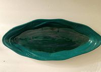 Top-down view of elongated ceramic plate showing greeny blue glaze with purple swirls and smooth glossy finish.