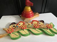 Photo showing large stacked wooden duck toy with colorful rings and Bartolucci bird clothes hanger below