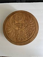 Top view of the circular wooden box lid showing detailed bird carving in Haida style with Clarence A. Wells signature.