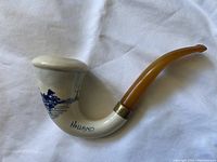 Full side view of the curved Dutch Calabash pipe with white bowl, hand-painted blue riverside scene, 'Holland' marked, amber stem with brass ring.