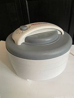 Side view of NESCO food dehydrator showing its stackable trays and lid with control panel.