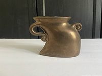 Side view showing the swirling handle and bronze glaze finish on the small artistic vase.
