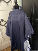 Full front view of navy blue MEC Aquanator poncho displayed on mannequin, showing loose rectangular shape and hood.