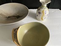 Three ceramic pottery pieces on white surface: vase by Saundra Reiner, green bowl by Peter Michalski, and abstract design bowl by Louise Macnab