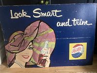 Full view of the vintage Pepsi-Cola advertising poster with woman holding a bottle and text 'Look Smart and trim' on dark blue background.