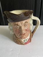 Front and side views of the Royal Doulton Sam Johnson character jug showing detailed facial features, hat, and handle