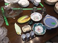 Clear three-footed glass bowl with silver overlay and matching candleholders on table with other dishes