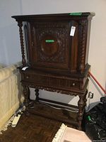 Front view of the carved walnut cabinet, showing central carved panel and barley twist columns