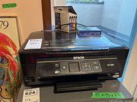 Epson XP-300 printer on a table with ink cartridges placed on top.