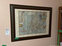 Framed map printed on paper, mounted on the wall, showing England and Wales with decorative borders and sea illustrations.