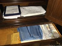 White Irish cotton damask napkins and folded white linens stacked in a cabinet drawer.