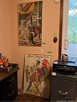 Photo shows two framed Shaw Festival prints in a room setting, one mounted on the wall (1981) and one leaning against a filing cabinet (1979).