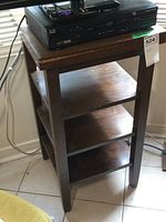 Full view of wooden 4-level shelf unit with contents removed, showing dark stained wood, visible wear marks, and modest size.