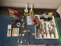 Full lot overview showing utensil tray with silver plated utensils, candlesticks, napkin rings, wine stoppers, and other kitchen and table accessories.
