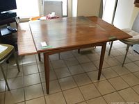Table assembled with two leaves extended on opposite sides, showing overall form and tapered legs