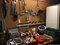 Photo of workbench surface showing toolbox, bottles, cords, tapes, and miscellaneous tools.