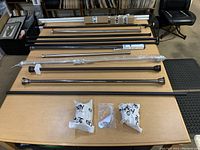 Photo showing multiple rods of different lengths and finishes arranged on a table with hardware bags visible.