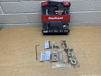 Photo of Kwikset SmartKey lever lock and deadbolt set in original packaging with hardware and manuals laid out.