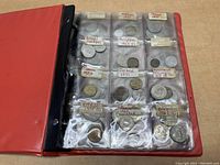Coins arranged in labeled plastic pockets inside a red binder.