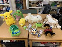 Photo showing a variety of stuffed animals including Pikachu, Bugs Bunny, turtle plushes, a white horse on wheels, a green frog, and other assorted plush toys on a wooden table.