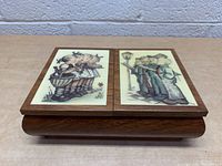 Top view of vintage Hummel style music box with two panels showing children singing and holding flowers